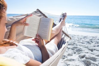 vrouw leest boek in hangmat op het strand